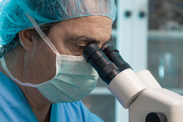 senior scientist looking through the microscope