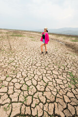 woman walking in dryland with drought ground texture. concept climate changed.