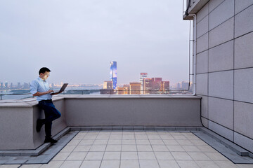 Businessman standing on the rooftop and using laptop