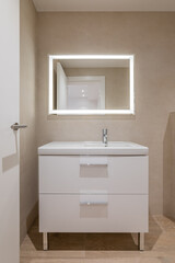 Fototapeta na wymiar Modern bathroom with beige tiles, furniture and rectangular large mirror with lighting