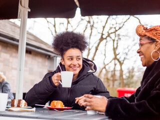 Mother with daughter sitting at outdoor cafe table