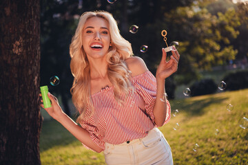 Photo of pretty cheerful wavy hairdo girl hold bottle soap water blow bubbles street outdoors
