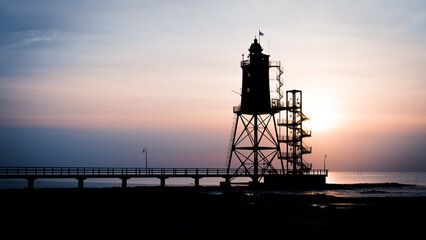 Fototapeta na wymiar Leuchtturm mit Steg bei Sonnenuntergang