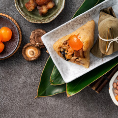 Zongzi, rice dumpling for Dragon Boat Festival on dark gray table background with ingredient.
