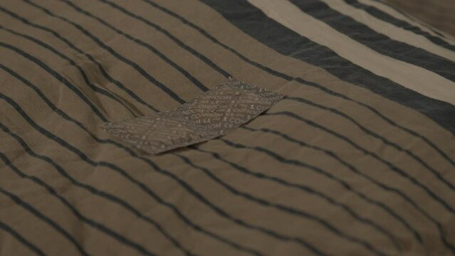 Close dolly in of pair of wrapped condoms lying on pillow on bed