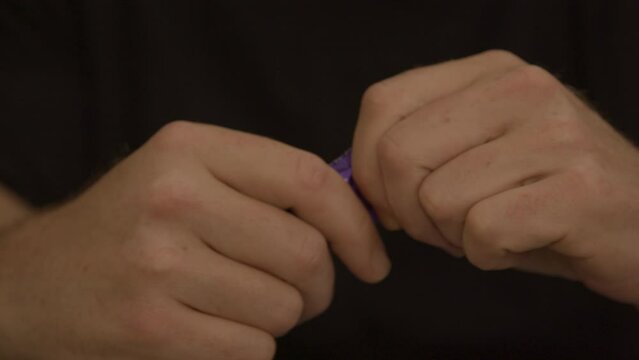 Male hands struggling to open purple condom package