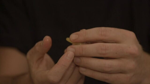 Man's hand showing condom to viewer