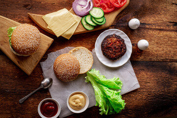 Hamburger day. Cooking hamburger or cheeseburger. Different ingredients for a classic hamburger. Place for text. Wooden background.