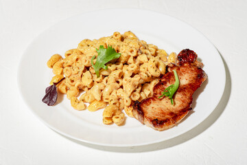 Pasta in cheese sauce with chopped meat and lettuce. Minimalistic food design. White background.