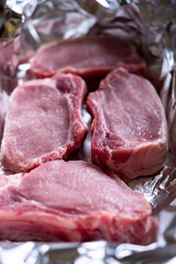 Raw meat steaks on foil. Pig meat. Preparation for cooking in the oven.