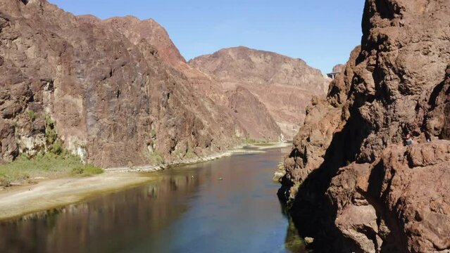 Aerial view of people sitting on cliffs watching rafts on the Colorado river - ascending, drone shot