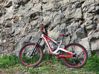Full suspension downhill bicycle at rocky stone wall background
