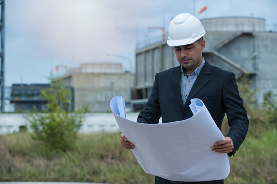 architect with blueprint. Construction workers, engineer hand hold drawing on power plant on background.