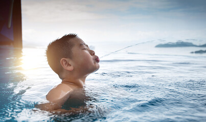 Boy swimming and spitting water from mouth - obrazy, fototapety, plakaty