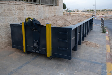 Dumpster Waste metal tank container filled with ground, rubble near a construction site.