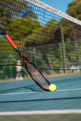 Fotobehang Surface level view of ball by racket leaning on tennis net at court during sunny day © wavebreak3