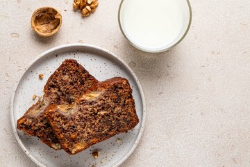 Traditional American homemade sliced banana bread with chopped walnuts, chocolate and cinnamon and milk on light background. Fruit cake. Pound cake. Breakfast background.