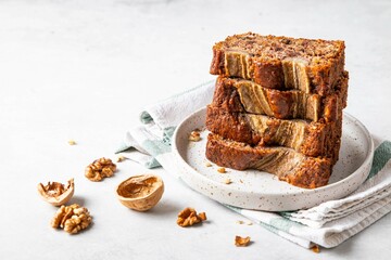 Pieces of american homemade sliced banana bread with chopped walnuts, chocolate and cinnamon. Stack of pieces of bread. Breakfast concept. Selective focus. Copy space for text.