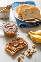 Nut butter toast with bananas and honey on light table. Walnut, hazelnut and cashew nut spread in...