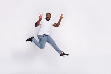 Fototapeta na wymiar Photo of pretty cute guy dressed casual t-shirt jumping high running v-sign empty space isolated white color background