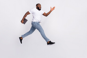 Fototapeta na wymiar Photo of excited funky guy dressed casual t-shirt jumping high holding modern gadget empty space isolated white color background