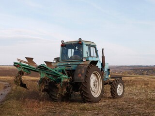 Fototapeta premium Old tractor with a plow on the field.