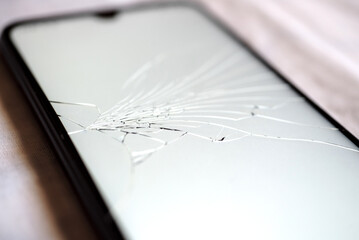 Close-up de un teléfono móvil encendido con la pantalla rota y llena de arañazos. Concepto de...
