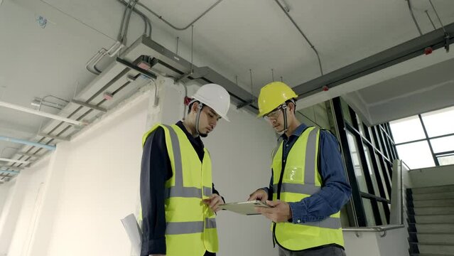 Concept augmented reality technology in construction business. Asian man Electrical Engineer team working inspection installation electrical system in building on tablet at construction site.