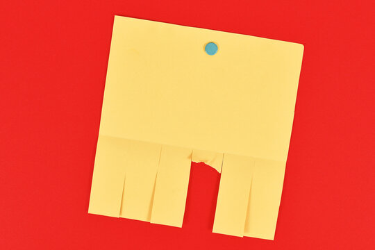 Empty yellow tear-off stub paper note without text on red background
