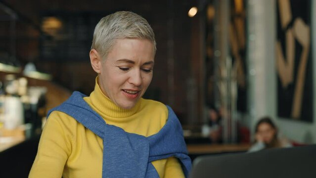 Stylish mature woman working on laptop at cozy cafe