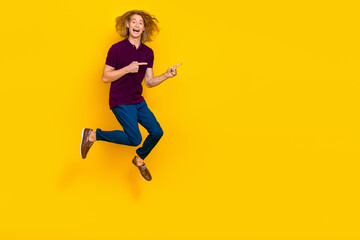 Fototapeta na wymiar Full size photo of overjoyed energetic man jumping direct fingers empty space isolated on yellow color background
