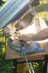 man's hands cutting wood on a circular saw