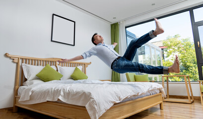 Excited man jumping to the bed
