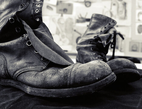 An up close picture of weathered and beaten up mens industrial work boots. 