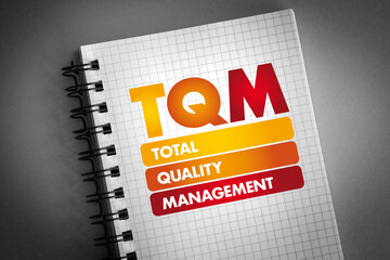 TQM - Total Quality Management acronym on notepad, business concept background