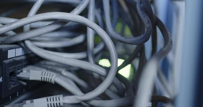 Close-up, a gloved hand unplugs an internet cable from a switch node jack. Disable access to information.