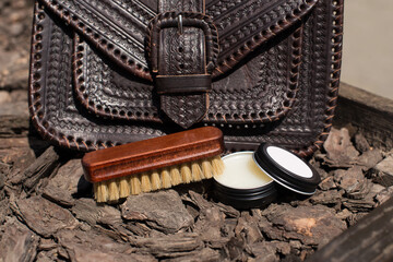 Wax and brush, leather maintenance concept. old genuine leather bag on a background.