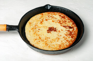 Swiss traditional dish - potato pancakes fried in a frying pan on a light background close-up.