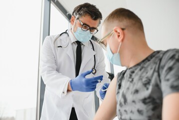 medicine, vaccination and healthcare concept - doctor wearing face protective medical mask for...