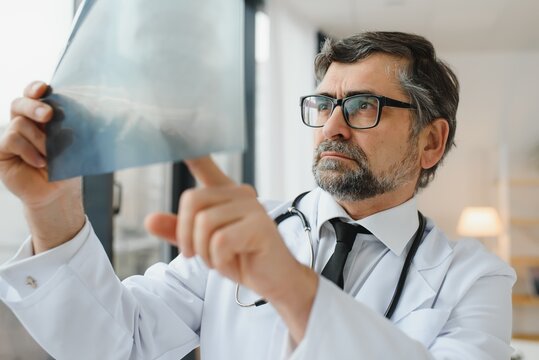 older man doctor examines x-ray image of lungs in a clinic