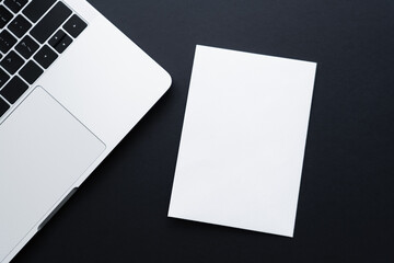 top view of blank paper near laptop on black. - obrazy, fototapety, plakaty
