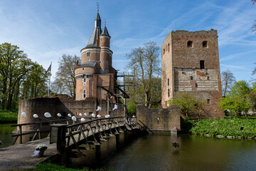 Wooden access bridge leading to remains and round fairy-tail tower of picturesque moated Duurstede castle against a blue sky