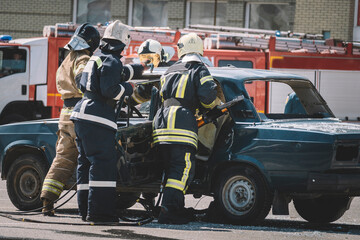 first aid after an accident on the road. Fireman with protective overalls and work gloves while...