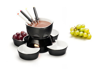 Modern black and white ceramic foundue kit, with chocolate, and grapes on the side, isolated