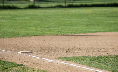 baseball field base, white baseline, green grass, sunny spring day