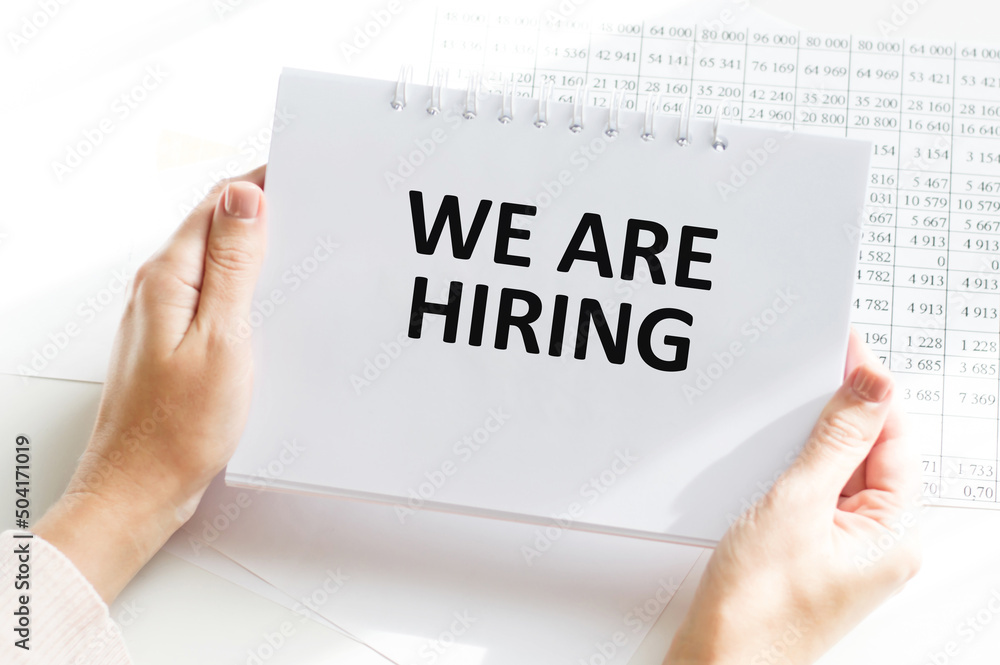 Poster we're hiring text with notepad holding a man on the background of your desktop