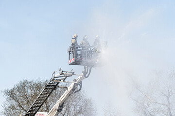 Firefighter works on boom of fire engine. Fireman on sky background. Rescuers on a retractable...
