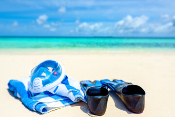 Fins, a towel and an underwater mask on the sand on the shore of the Indian Ocean.