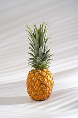 Juicy pineapple on a white background. A whole pineapple and a cut off half. Palm tree shade, creative lighting.