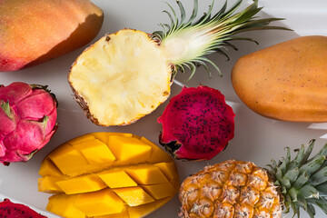 Assorted various tropical Asian fruits. Mango, pineapple, pitahaya, whole and cut, on a white background.